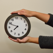 Twee handen die een analoge klok vasthouden